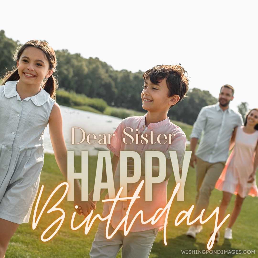 Two cute little children holding hands and smiling while walking on green grass with their parents. 